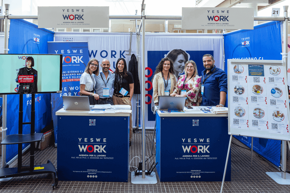 Recruiter e altri rappresentanti di YesWeWork sorridono al loro stand durante il Job Meeting 2023 al Politecnico di Bari