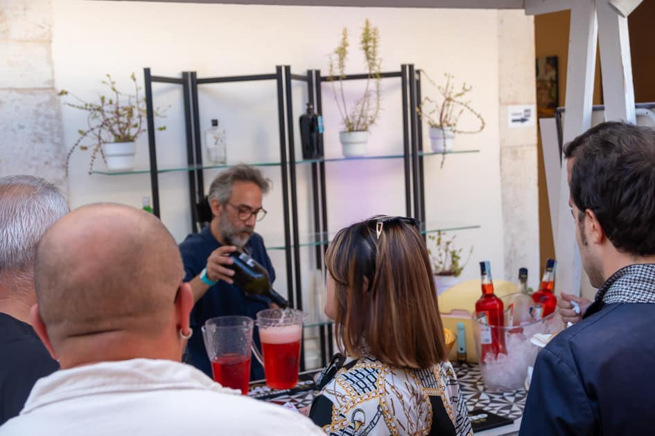 Delle persone sono di fronte al bancone del Bar dell'ApeRecruiting Job Day mentre il barista prepara aperitivi per tutti