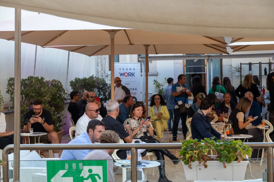 Area Aperitivo dell'ApeRecruiting Job Day di Trani. Molti dei partecipanti sono seduti ai tavoli e si rilassano