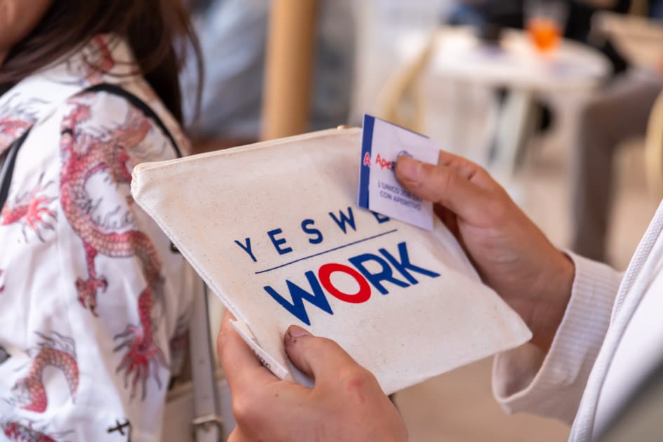 Uno dei partecipanti regge tra le mani la pochette omaggio di YesWeWork e i ticket food e drink all'ApeRecruiting