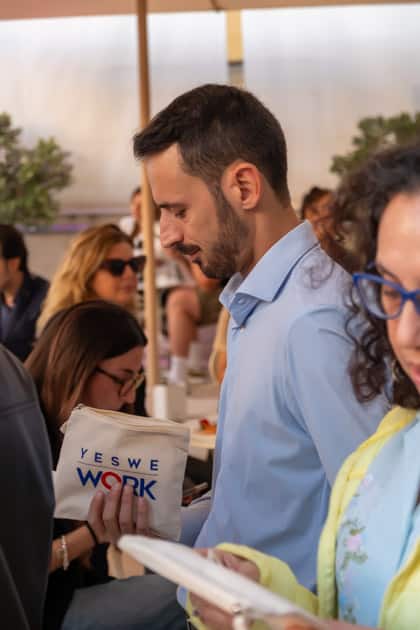 Due partecipanti all'ApeRecruiting di Trani guardano la pochette omaggio regalatagli da YesWeWork