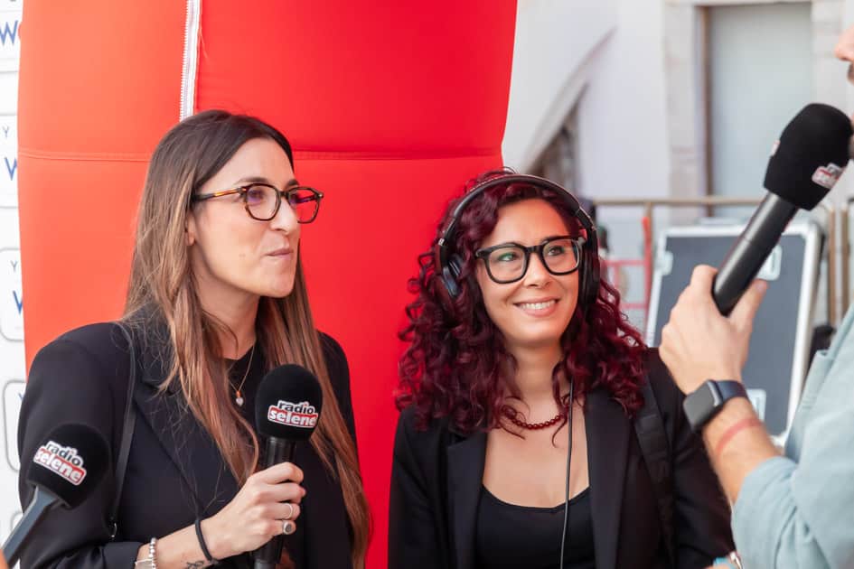 Due ragazze sorridenti vengono intervistate da Radio Selene durante l'evento YesWeWork 'ApeRecruiting Job Day Trani'