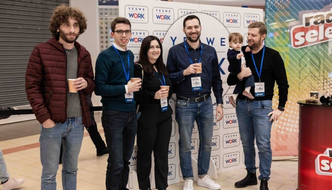 Alcuni membri del team YesWeWork sorride in posa per una foto. Uno di loro ha in braccio la propria figlioletta