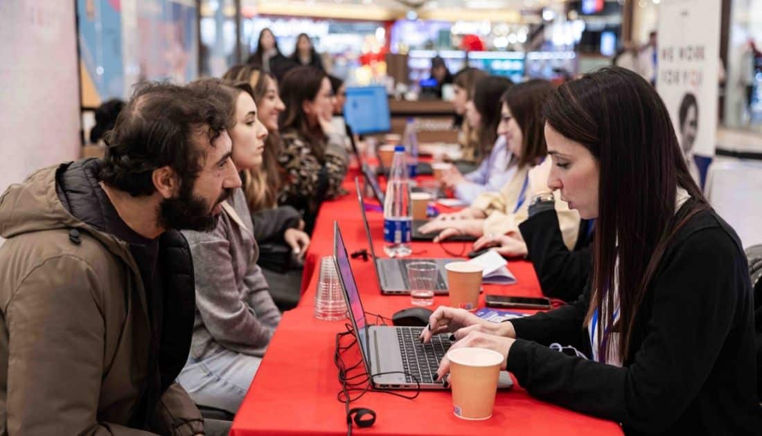 Inquadratura laterale dei banchi allestiti per i colloqui di lavoro all'ApeRecruiting. Tutte le postazioni sono piene
