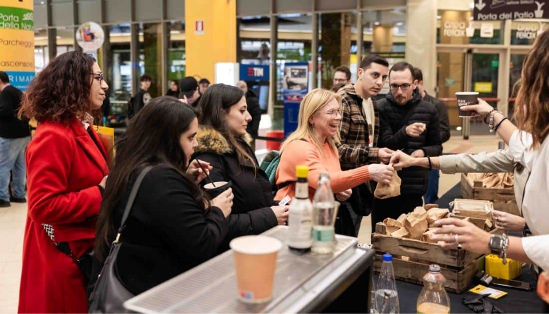 Alcune persone sono alla zona Catering dell'ApeRecruiting per ritirare le proprie consumazioni offerte da YesWeWork