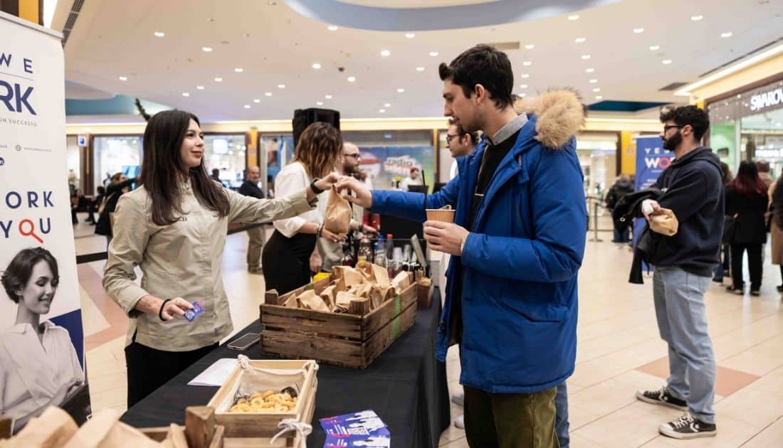 Uno dei ragazzi presenti all'ApeRecruiting ritira un sacchetto di finger food offerto da YesWeWork presso l'area aperitivo