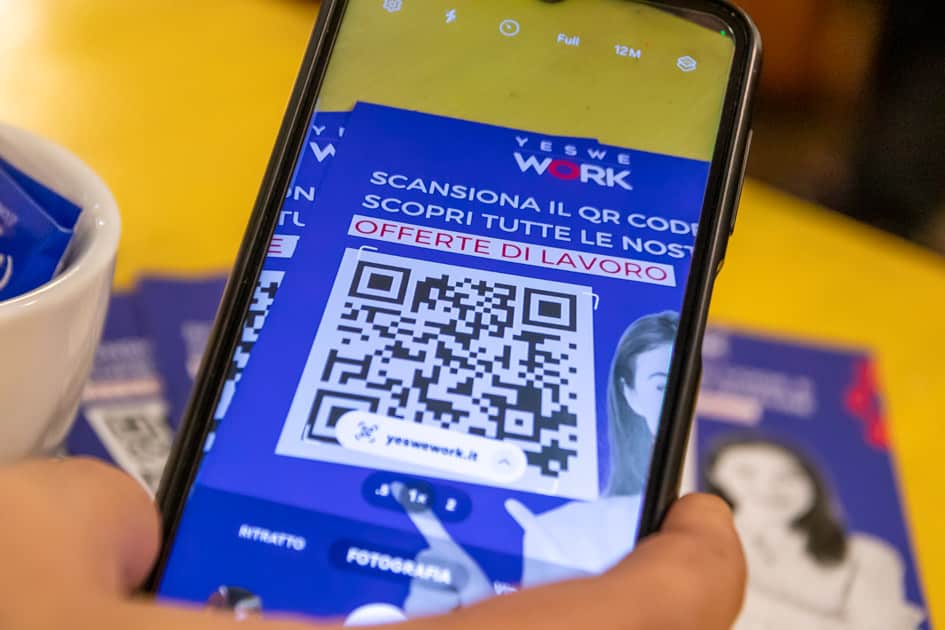 Uno smartphone che scansiona il QR Code sui volantini di YesWeWork che porta alla pagina degli annunci di lavoro
