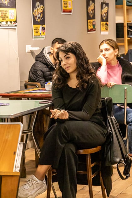 Una ragazza partecipante all'evento Caffè con YesWeWork seduta ad un tavolino segue interessata lo speech della relatrice