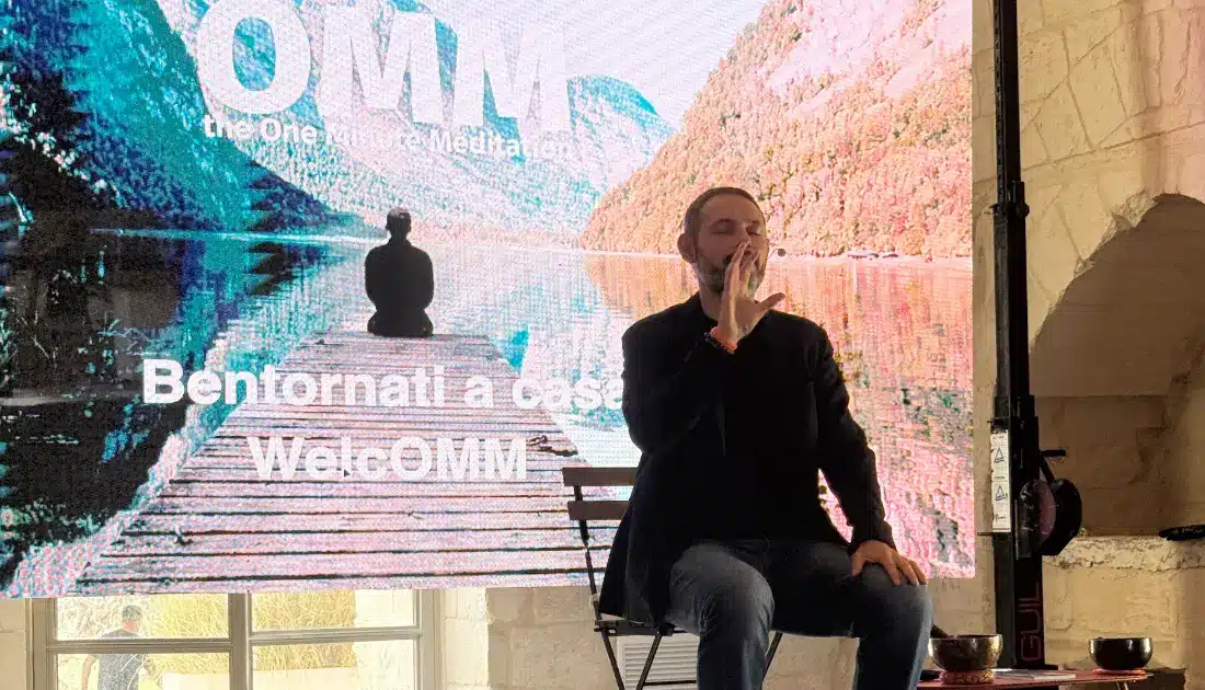 Fabio Cutrera, seduto su una sedia al centro del palco, fa un esercizio di OMM (One Minute Meditation) con il suo pubblico