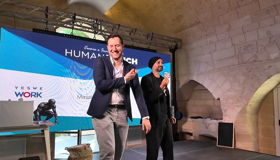 Antonio Giacobelli di YesWeWork ride sul palco di fianco ad Andrea Paris che tiene in mano un biglietto con la scritta 'NO'