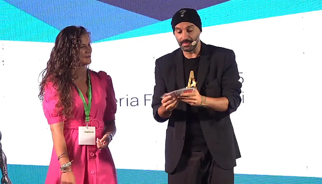 Andrea Paris si appresta a fare un trucco con un mazzo di carte coinvolgendo sul Palco la recruiter di YesWeWork Santa