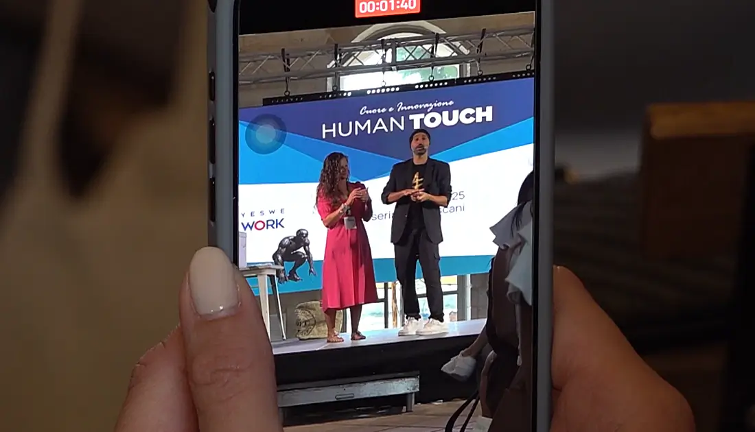 Uno smartphone in primo piano sta riprendendo l'esibizione di Andrea Paris insieme a una recruiter di YesWeWork