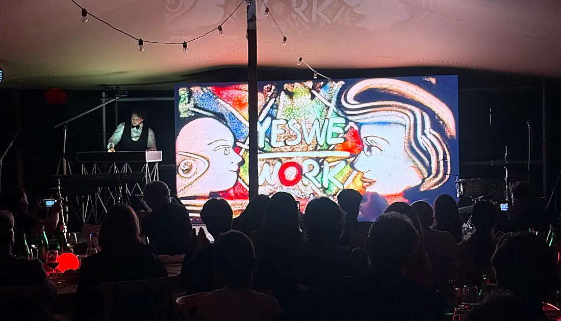 Il sand artist Andrea Arena conclude la sua esibizione con un quadro di sabbia che riporta il logo di YesWeWork