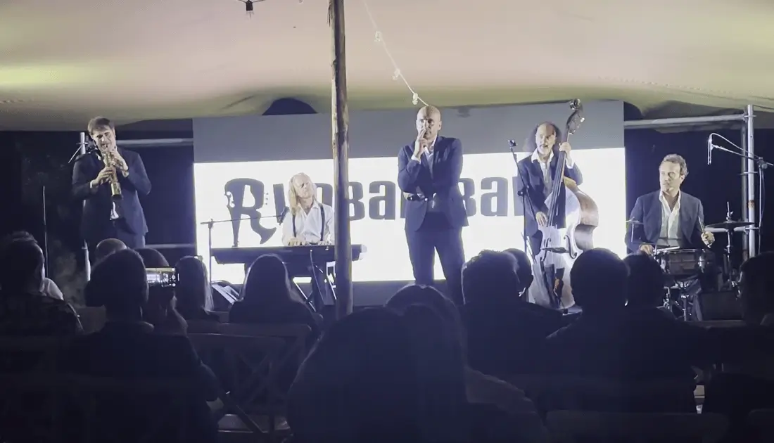 Il cantante della 'Rimbamband' mima il gesto di fumare una sigaretta mentre gli altri membri della band eseguono un brano