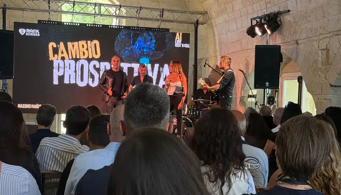 Max Panìco e band sul palco di 'Human Touch'. Sul maxischermo compare la scritta 'cambio prospettiva'