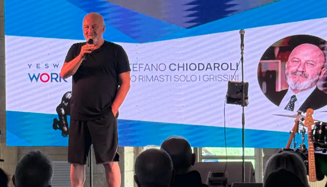 Stefano Chiodaroli in maglietta e pantaloncini neri parla al pubblico di 'Human Touch' durante il suo monologo comico