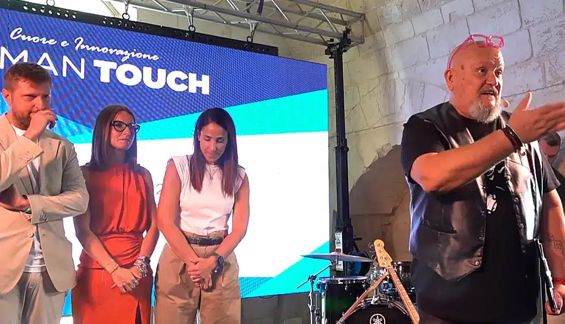 Enrico Piacentini parla al pubblico mentre alle sue spalle ci sono dei membri del team YesWeWork pronti per i saluti finali