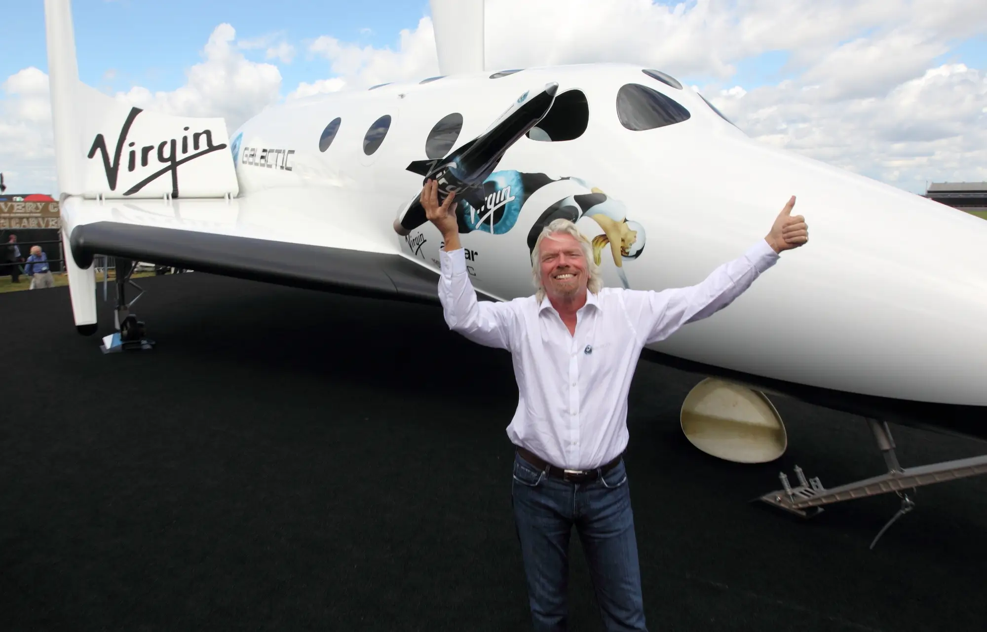 Richard Branson posa davanti alla navicella ‘SpaceShipTwo’ di ‘Virgin Galactic’ tenendone in mano un modellino in miniatura