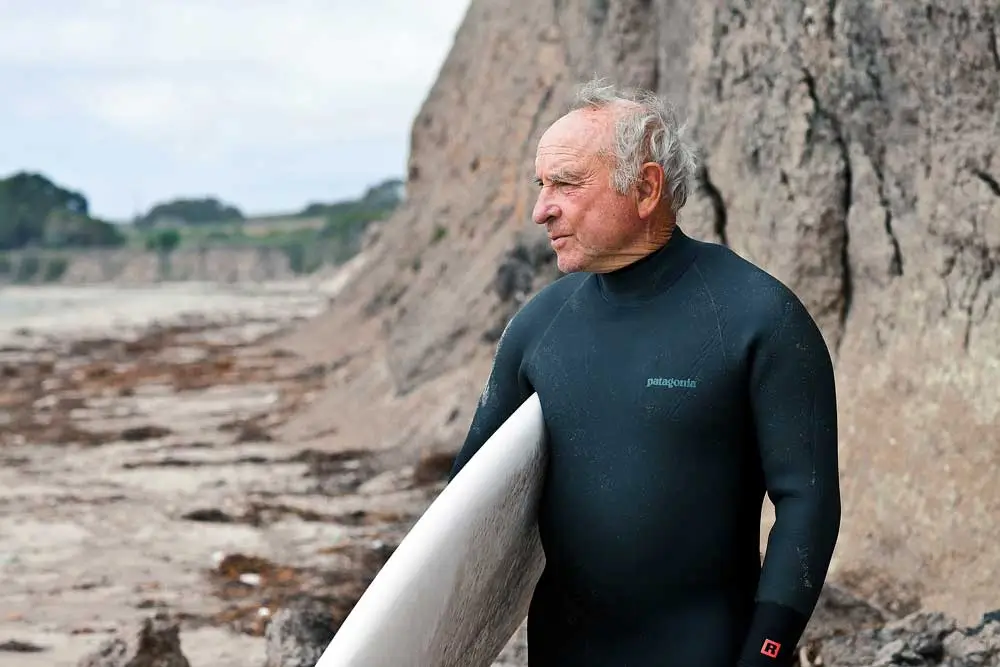 Yvon Chouinard con la sua tavola da surf contempla l’orizzonte su una scogliera californiana